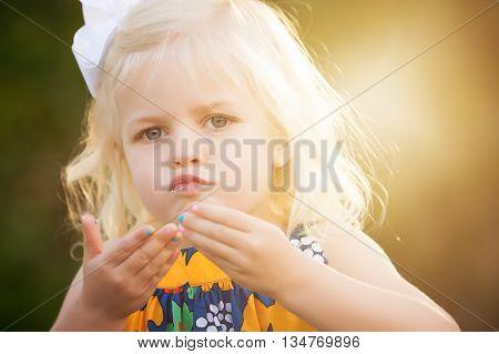 Blonde little 3 year old girl with glitter on lips and painted fingernails