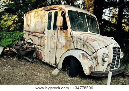 Decaying old milk truck with no wheels.