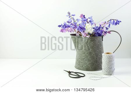 Styled stock floral image bluebells in a little tin jug. Copy space for your business promotion instagram message or headline.