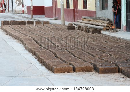 Magdalena Cajamarca Peru - June 16 2016: Woman sweeps sidewalk as adobe bricks dry in the sun in Magdalena Cajamarca Peru on June 16 2016