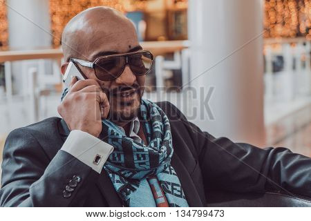 Arab businessman talking on mobile phone at a shopping center