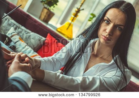 Man and the stylish girl sitting and holding hands in the restaurant