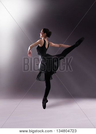 Young woman makes exercise isolated on gray background