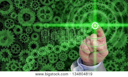 Different sized an shaped green cogs and gears background with a hand pressing a glowing green gear in a chain