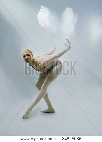 Young ballerina dancing with flour in studio