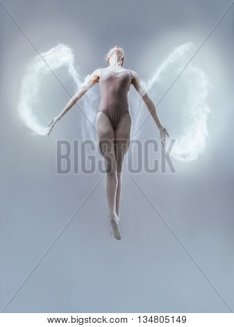 Young ballerina jumping with flour on blue background