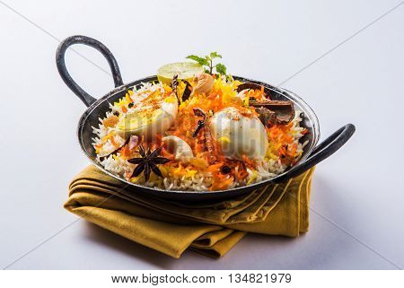 Basmati rice slowly cooked with Masala roasted egg and spices served in kadhai or kadai with yogurt dip, selective focus, egg biryani or anda rice or egg rice