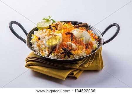 Basmati rice slowly cooked with Masala roasted egg and spices served in kadhai or kadai with yogurt dip, selective focus, egg biryani or anda rice or egg rice