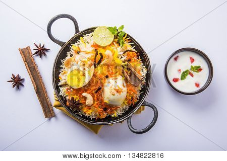 Basmati rice slowly cooked with Masala roasted egg and spices served in kadhai or kadai with yogurt dip, selective focus, egg biryani or anda rice or egg rice