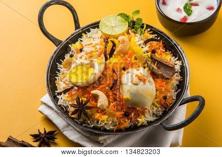 Basmati rice slowly cooked with Masala roasted egg and spices served in kadhai or kadai with yogurt dip, selective focus, egg biryani or anda rice or egg rice
