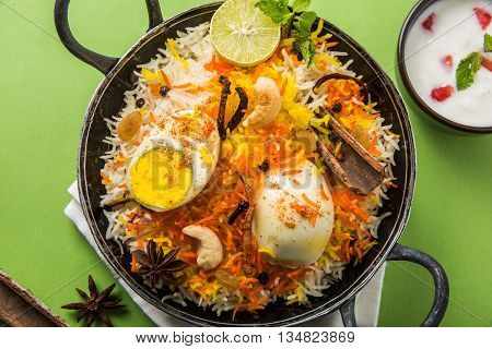 Basmati rice slowly cooked with Masala roasted egg and spices served in kadhai or kadai with yogurt dip, selective focus, egg biryani or anda rice or egg rice