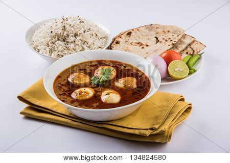egg curry with roti/chapati and jeera rice, tasty and spicy anda curry with roti and rice, indian egg masala curry served in ceramic bowl with roti, salad and jeera rice