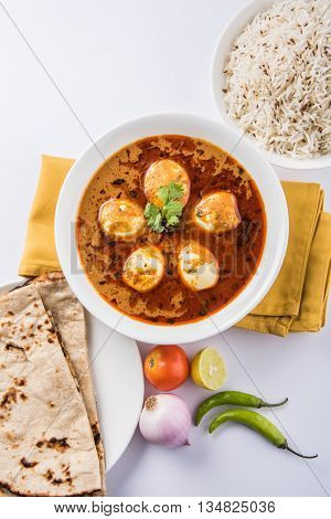 egg curry with roti/chapati and jeera rice, tasty and spicy anda curry with roti and rice, indian egg masala curry served in ceramic bowl with roti, salad and jeera rice