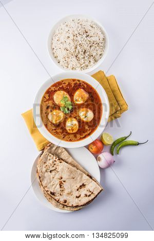 egg curry with roti/chapati and jeera rice, tasty and spicy anda curry with roti and rice, indian egg masala curry served in ceramic bowl with roti, salad and jeera rice