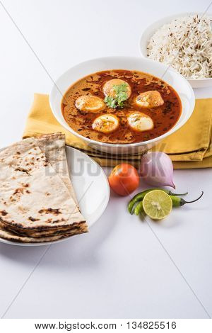 egg curry with roti/chapati and jeera rice, tasty and spicy anda curry with roti and rice, indian egg masala curry served in ceramic bowl with roti, salad and jeera rice