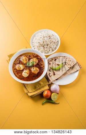 egg curry with roti/chapati and jeera rice, tasty and spicy anda curry with roti and rice, indian egg masala curry served in ceramic bowl with roti, salad and jeera rice