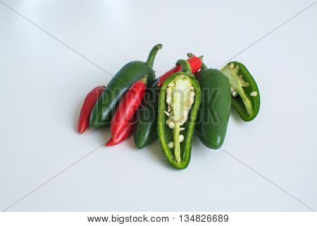Bright green jalapeno hot peppers and birdseye chilli peppers on white background