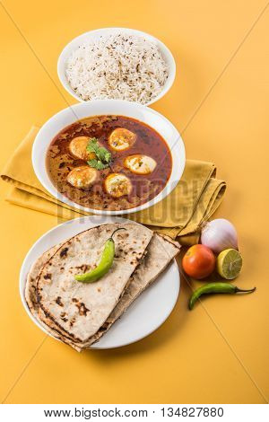 egg curry with roti/chapati and jeera rice, tasty and spicy anda curry with roti and rice, indian egg masala curry served in ceramic bowl with roti, salad and jeera rice