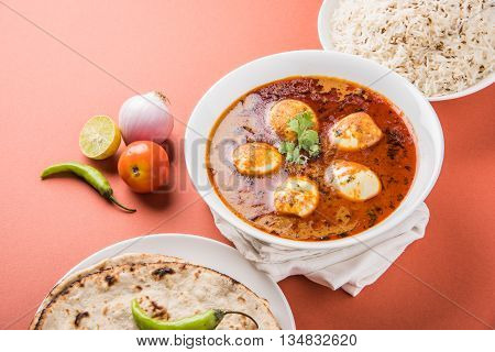 egg curry with roti/chapati and jeera rice, tasty and spicy anda curry with roti and rice, indian egg masala curry served in ceramic bowl with roti, salad and jeera rice