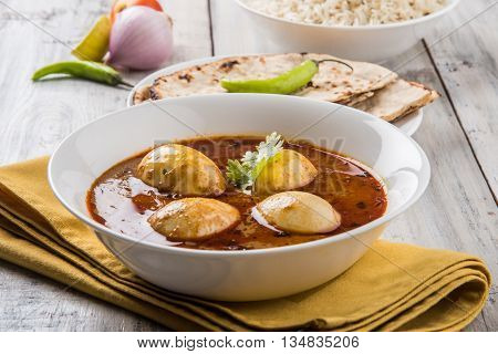egg curry with roti/chapati and jeera rice, tasty and spicy anda curry with roti and rice, indian egg masala curry served in ceramic bowl with roti, salad and jeera rice