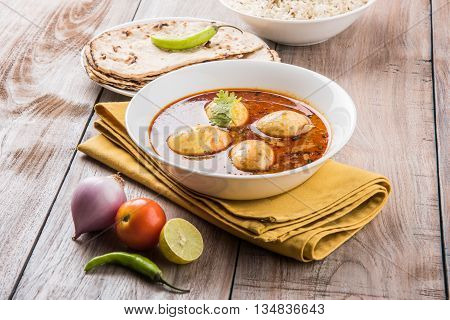 egg curry with roti/chapati and jeera rice, tasty and spicy anda curry with roti and rice, indian egg masala curry served in ceramic bowl with roti, salad and jeera rice