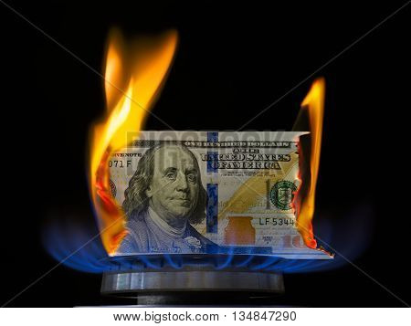 Dollar bill on fire in gas burner flame. Gas burner burning one hundred dollar bill.
