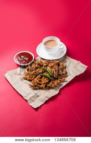 Crispy onion bhaji or kanda bhaji or fried onion pakore or pakode, delicious street food, favourite indian snack in monsoon served with hot tea