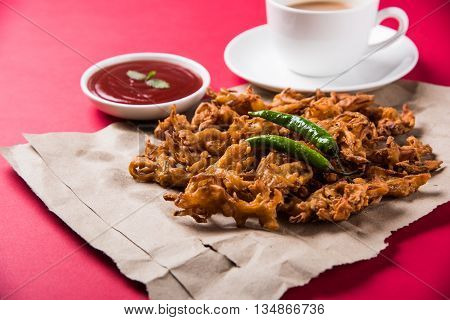 Crispy onion bhaji or kanda bhaji or fried onion pakore or pakode, delicious street food, favourite indian snack in monsoon served with hot tea
