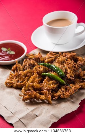 Crispy onion bhaji or kanda bhaji or fried onion pakore or pakode, delicious street food, favourite indian snack in monsoon served with hot tea
