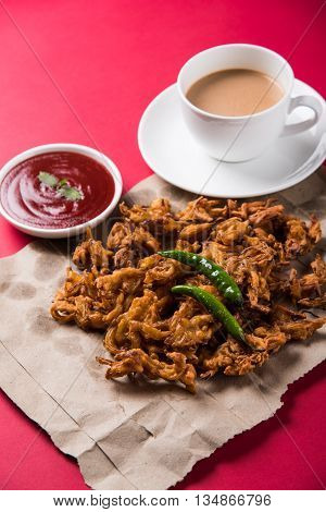 Crispy onion bhaji or kanda bhaji or fried onion pakore or pakode, delicious street food, favourite indian snack in monsoon served with hot tea