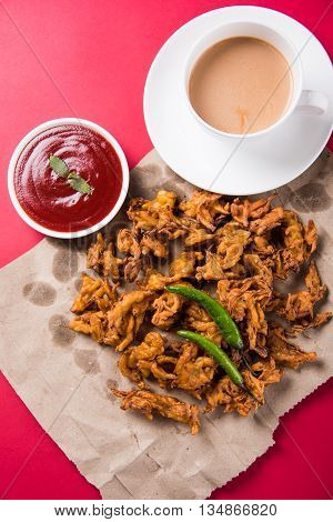 Crispy onion bhaji or kanda bhaji or fried onion pakore or pakode, delicious street food, favourite indian snack in monsoon served with hot tea