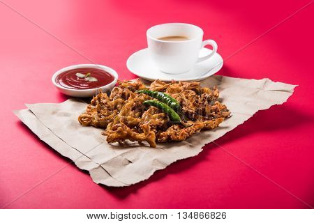 Crispy onion bhaji or kanda bhaji or fried onion pakore or pakode, delicious street food, favourite indian snack in monsoon served with hot tea