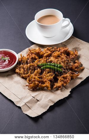 Crispy onion bhaji or kanda bhaji or fried onion pakore or pakode, delicious street food, favourite indian snack in monsoon served with hot tea