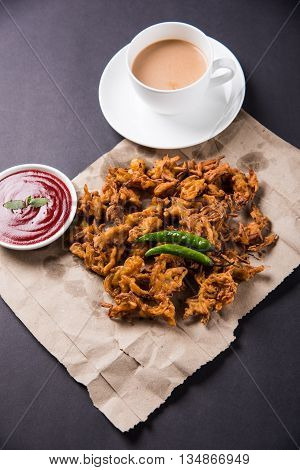 Crispy onion bhaji or kanda bhaji or fried onion pakore or pakode, delicious street food, favourite indian snack in monsoon served with hot tea
