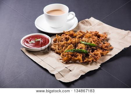 Crispy onion bhaji or kanda bhaji or fried onion pakore or pakode, delicious street food, favourite indian snack in monsoon served with hot tea