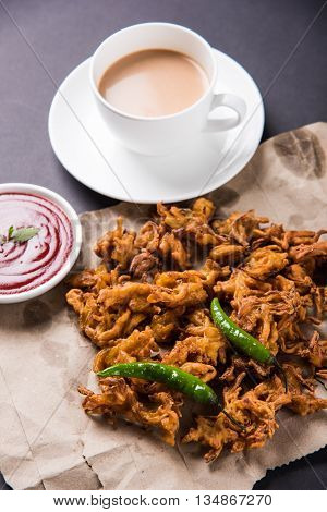 Crispy onion bhaji or kanda bhaji or fried onion pakore or pakode, delicious street food, favourite indian snack in monsoon served with hot tea