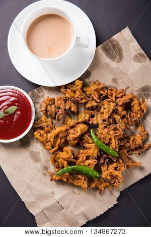 Crispy onion bhaji or kanda bhaji or fried onion pakore or pakode, delicious street food, favourite indian snack in monsoon served with hot tea