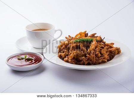 Crispy onion bhaji or kanda bhaji or fried onion pakore or pakode, delicious street food, favourite indian snack in monsoon served with hot tea