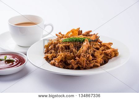 Crispy onion bhaji or kanda bhaji or fried onion pakore or pakode, delicious street food, favourite indian snack in monsoon served with hot tea