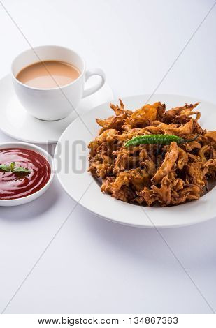 Crispy onion bhaji or kanda bhaji or fried onion pakore or pakode, delicious street food, favourite indian snack in monsoon served with hot tea