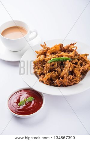 Crispy onion bhaji or kanda bhaji or fried onion pakore or pakode, delicious street food, favourite indian snack in monsoon served with hot tea