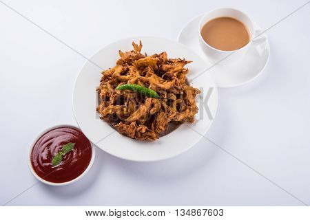 Crispy onion bhaji or kanda bhaji or fried onion pakore or pakode, delicious street food, favourite indian snack in monsoon served with hot tea
