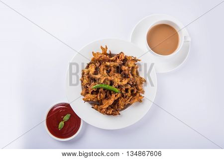 Crispy onion bhaji or kanda bhaji or fried onion pakore or pakode, delicious street food, favourite indian snack in monsoon served with hot tea