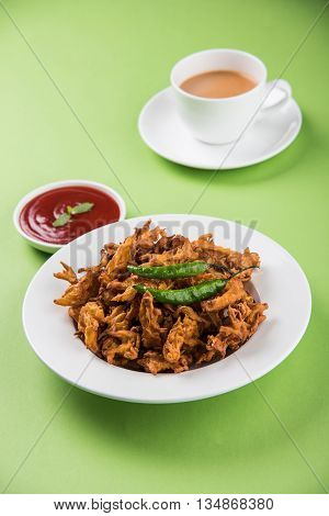 Crispy onion bhaji or kanda bhaji or fried onion pakore or pakode, delicious street food, favourite indian snack in monsoon served with hot tea