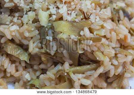 Brown rice with carciofi and grated cheese on the plate close-up.
