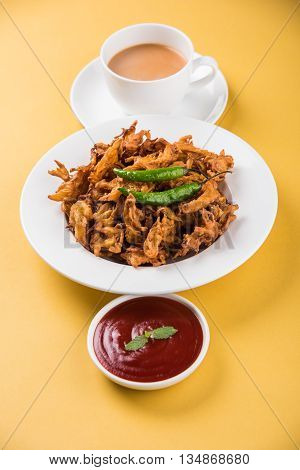 Crispy onion bhaji or kanda bhaji or fried onion pakore or pakode, delicious street food, favourite indian snack in monsoon served with hot tea