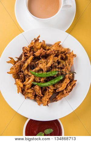 Crispy onion bhaji or kanda bhaji or fried onion pakore or pakode, delicious street food, favourite indian snack in monsoon served with hot tea