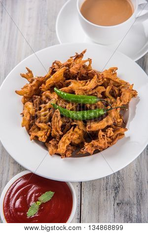 Crispy onion bhaji or kanda bhaji or fried onion pakore or pakode, delicious street food, favourite indian snack in monsoon served with hot tea
