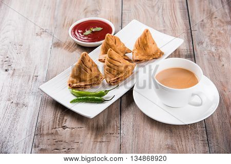 Samosa snack with tomato ketchup and hot tea, Fresh samosas with ketchup and hot chai ready for breakfast