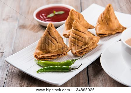 Samosa snack with tomato ketchup and hot tea, Fresh samosas with ketchup and hot chai ready for breakfast